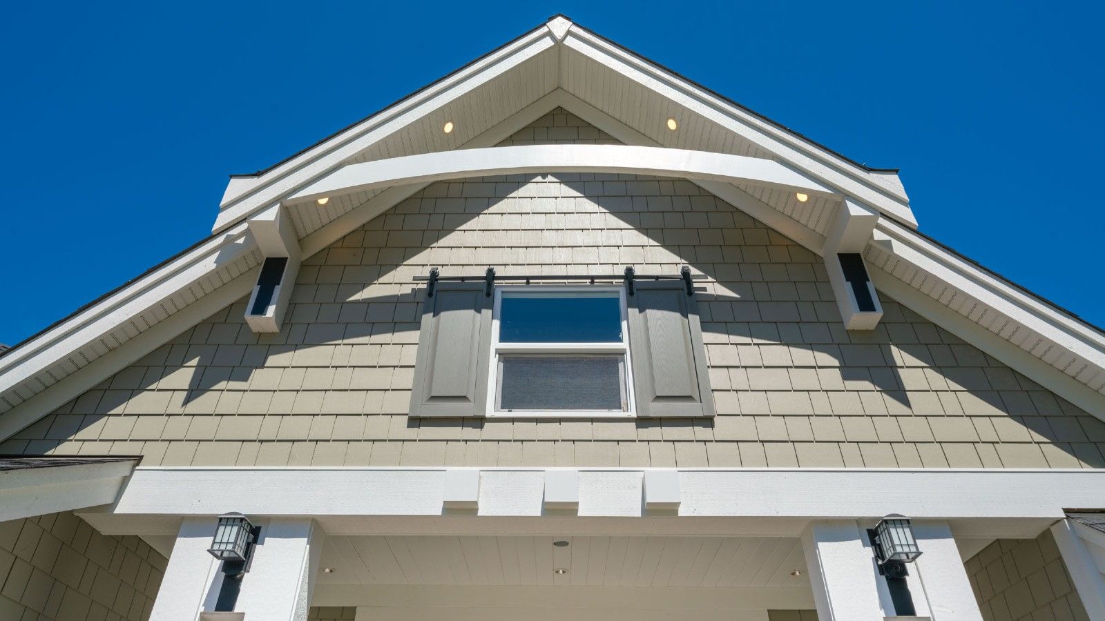 Image looking up at the front of a home with a blue sky in the background.