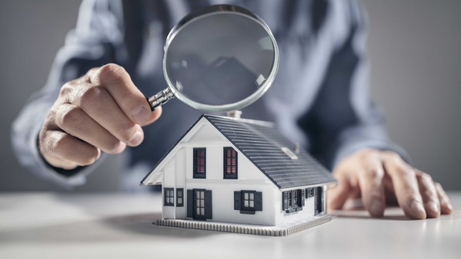 House with man holding magnifying glass concept for home inspection or searching for a new house