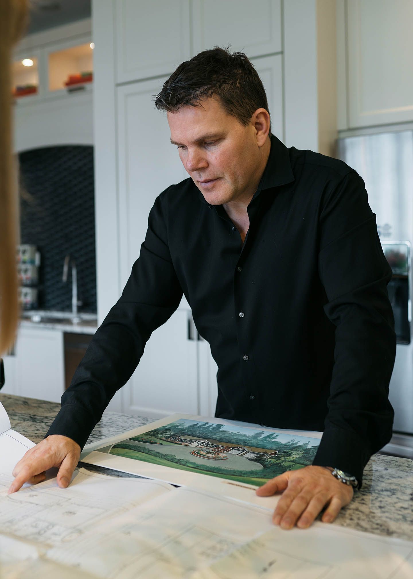 Man in black shirt looking a pictures on a table