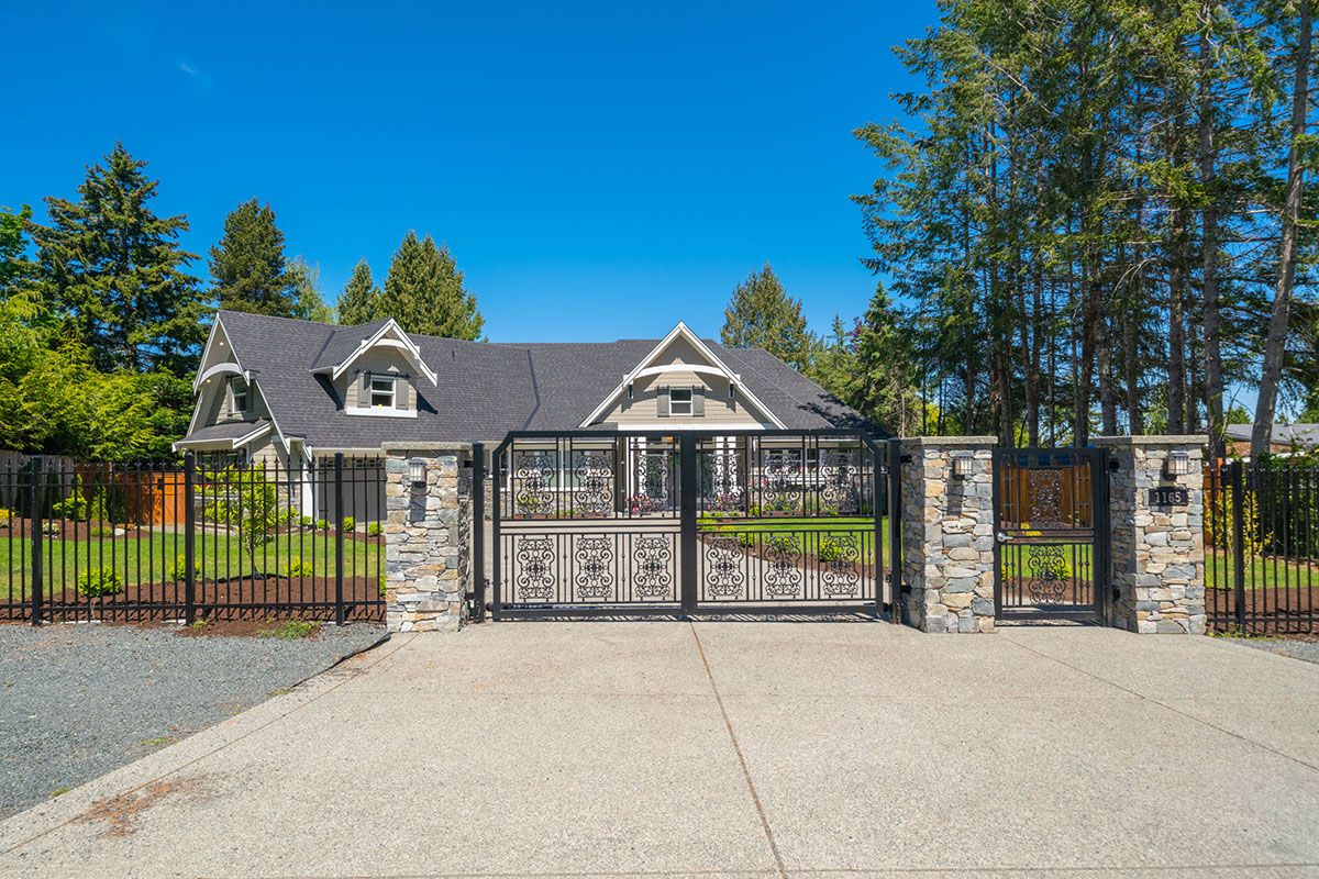 Large grey house behind black metal gate