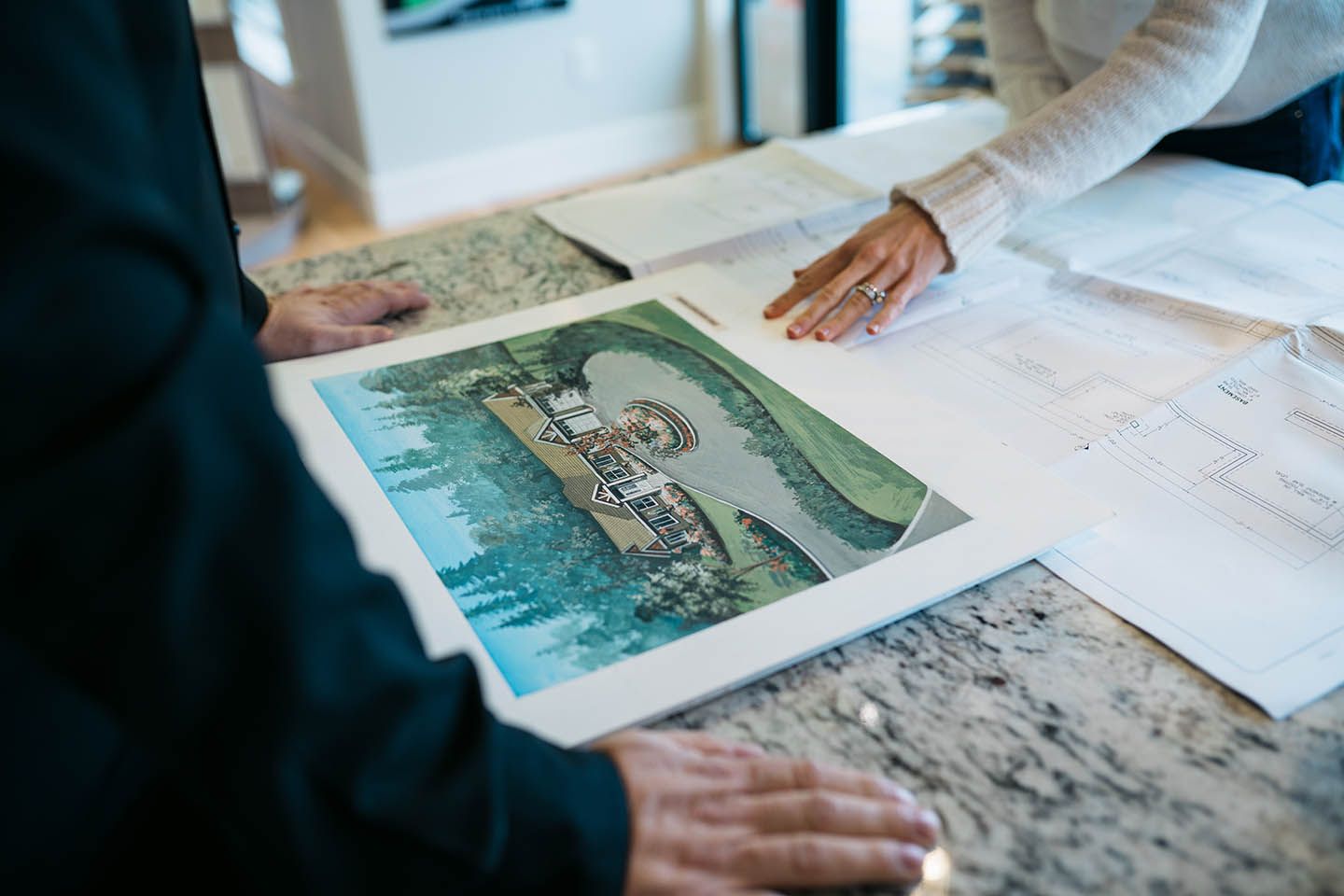 Two peoples hands on a table looking at design plans