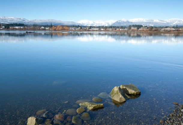 Photo of comox valley shore with ocean, mountains and blue skies in the background near Courtenay BC