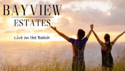 Two people on the beach with arms outstretched looking at the sunset.