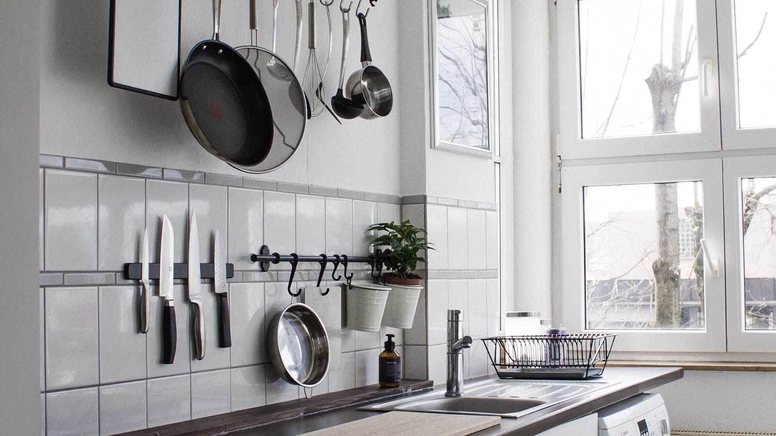 A view of some kitchen storage ideas including a magnetic knifeblock and pans hung up on the wall.