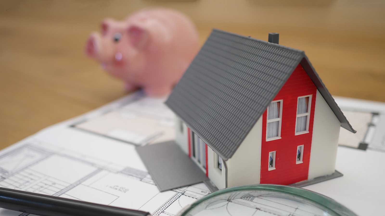 A piggy bank behind a model of a house.