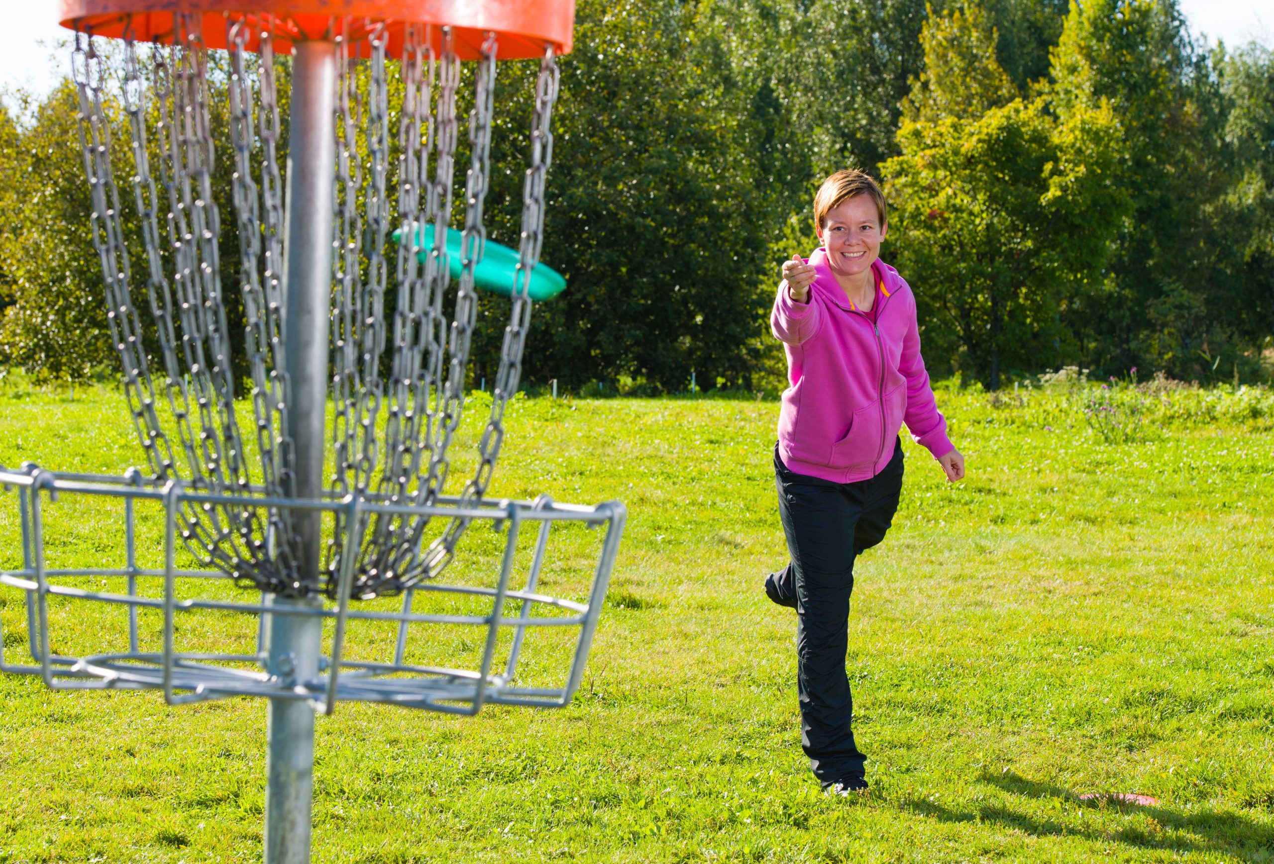 Woman throwing a disc to the disc basket