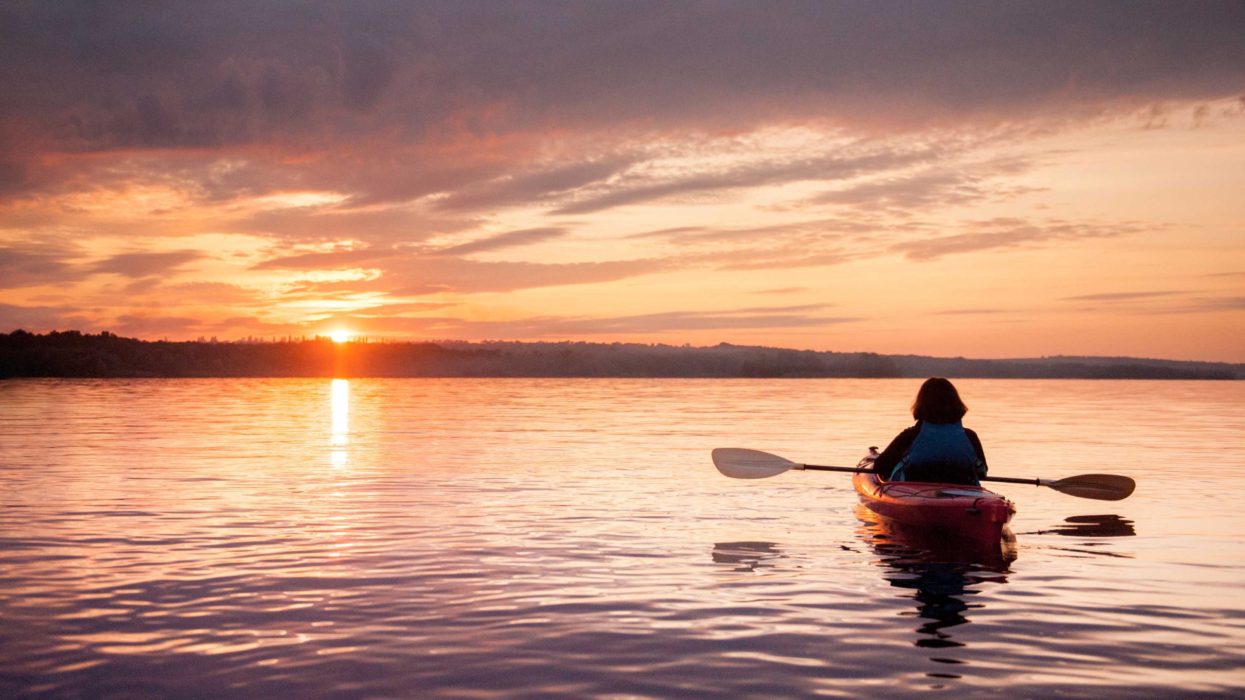 Woman in a kayak on the river on the scenic sunset