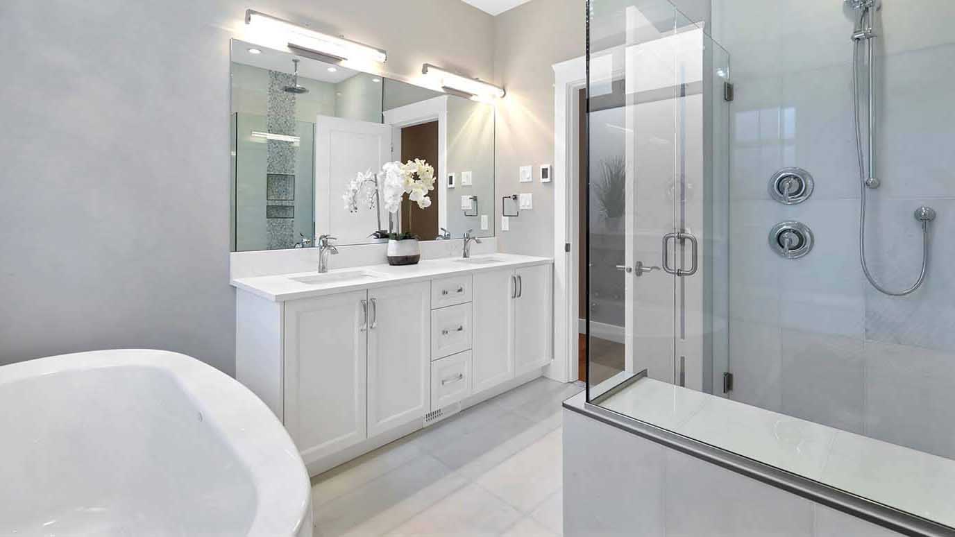 An immaculate bathroom featuring a large tub, shower, and his and hers double sinks. Designed by Ballard Fine Homes.