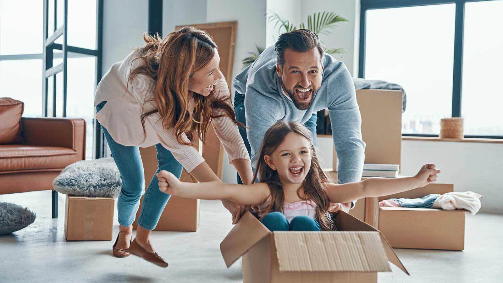Cheerful young family smiling and unboxing their stuff while moving into a new home.